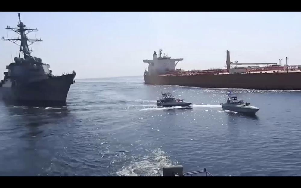 This frame grab from a video released by Iran's paramilitary Revolutionary Guard on Wednesday, Nov. 3, 2021, shows the Guard speed boats, center, in front of a U.S warship, left, amid the seizure of a Vietnamese-flagged oil tanker, right, in the Gulf of Oman. Iran seized the tanker in the Gulf of Oman last month and still holds the vessel, two U.S. officials told The Associated Press on Wednesday, revealing the latest provocation in Mideast waters as tensions escalate between Iran and the United States over Tehran's nuclear program. (Revolutionary Guard via AP)