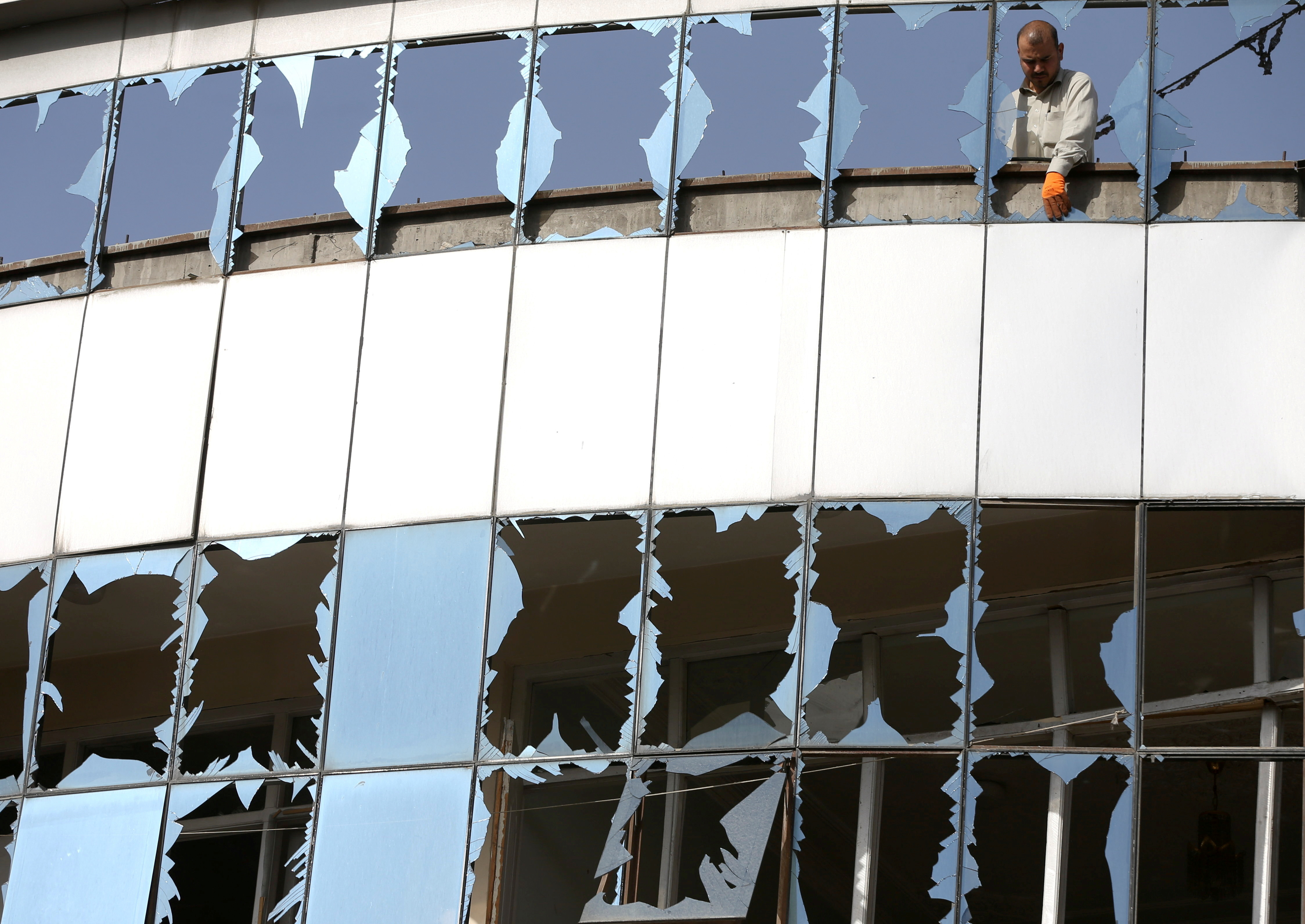 A man removes broken glasses from a window at the site of yesterday's night-time car bomb blast in Kabul, Afghanistan August 4, 2021. REUTERS/Stringer     