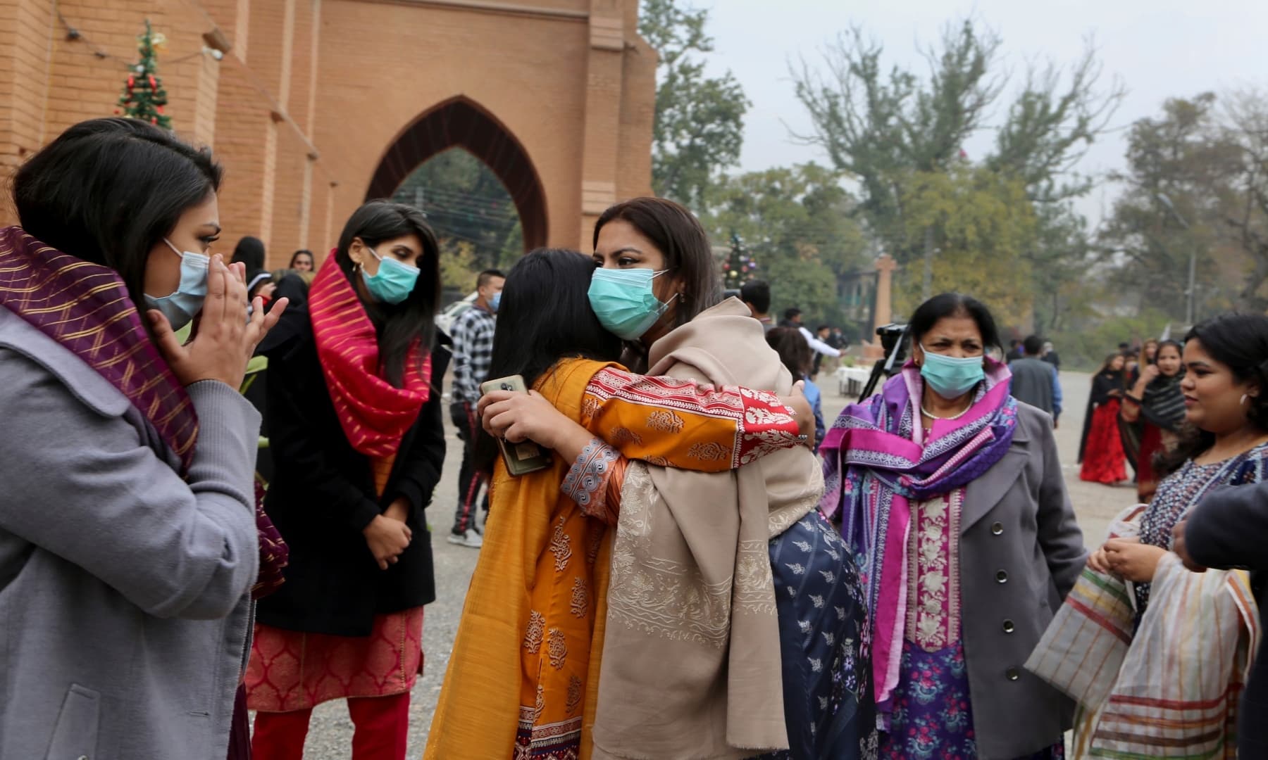 Christian women greet each other after attending a Christmas mass at St. John's Cathedral in Peshawar. — AP