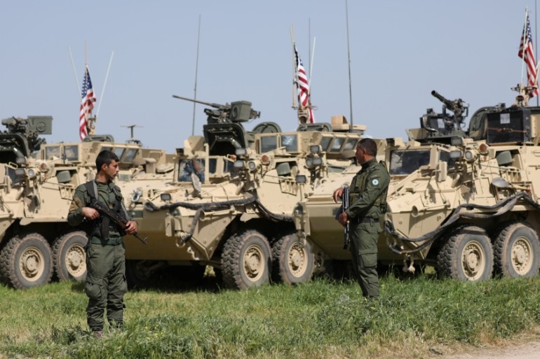 Kurdish fighters from the People's Protection Units (YPG) stand near US military vehicles in the town of Darbasiya next to the Turkish border, Syria April 29, 2017 [Rodi Said/Reuters]