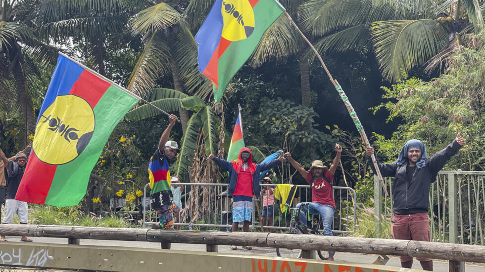 People wave New Caledonia independence flags during the 171st anniversary of France's takeover of the Pacific archipelago, 24 September 2024. While the Kanak independence movement continues to demand full self-determination, many French officials still see extending voting rights as essential for democratic fairness in the territory.