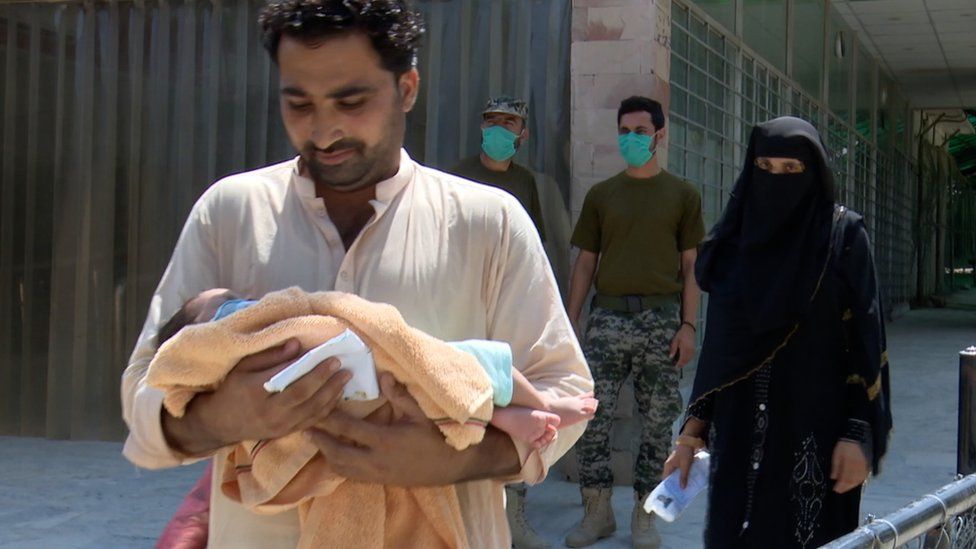 An Afghan man walks with a baby at the Torkham crossing on the Pakistani-Afghan border