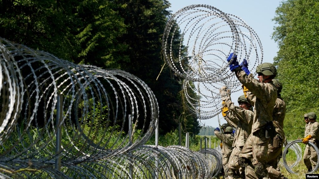 FILE - Lithuanian army soldiers install razor wire on the border with Belarus in Druskininkai, Lithuania, July 9, 2021. 