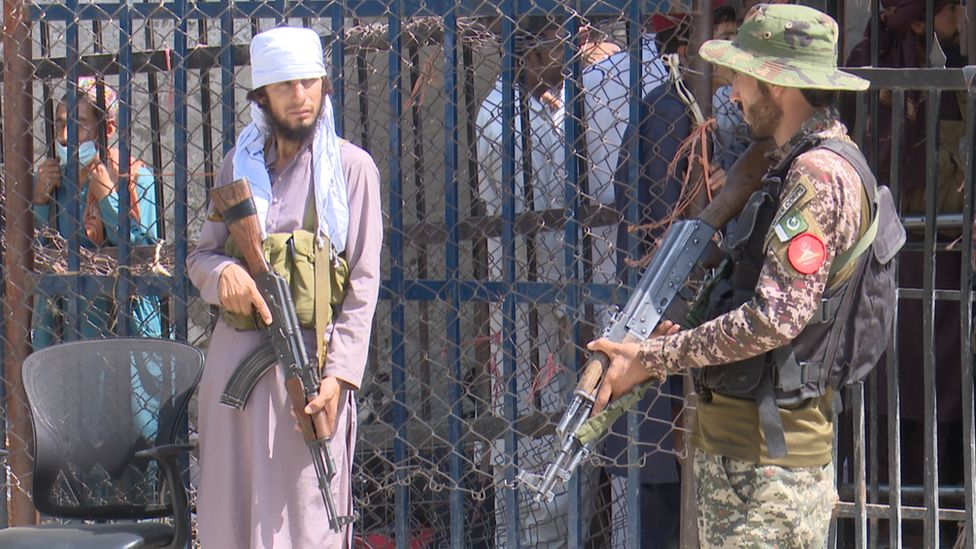 An armed Taliban fighter (left) and an armed Pakistani soldier at the Torkham crossing on the Pakistani-Afghan border