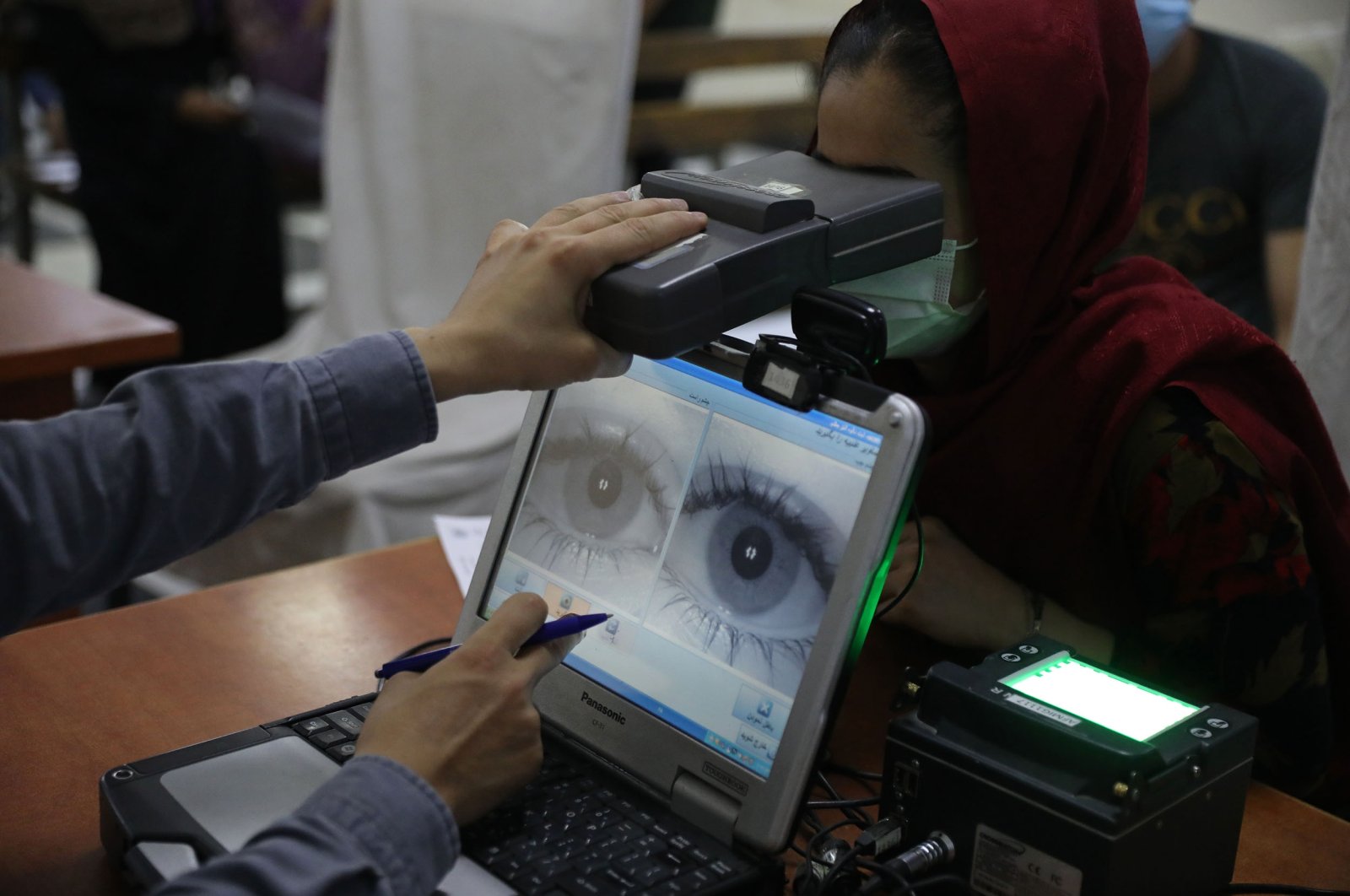 An employee scans the eyes of a woman for biometric data needed to apply for a passport, at the passport office in Kabul, Afghanistan, June 30, 2021. (AP Photo)