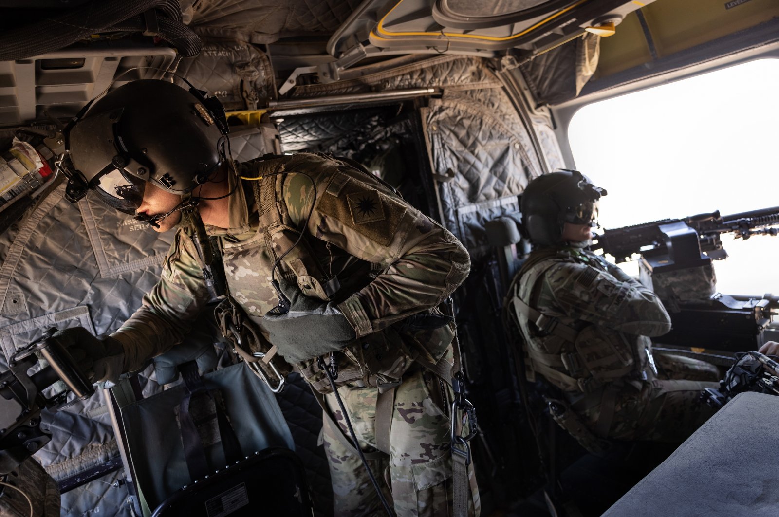 U.S. Army CH-47 Chinook helicopter gunners scan the desert while transporting troops on May 26, 2021 over northeastern Syria. U.S. forces, part of Task Force WARCLUB operate from remote combat outposts in northeastern Syria, coordinating with the YPG terror group in combatting residual Daesh extremists and deterring pro-Iranian militia. (Photo by Getty Images)