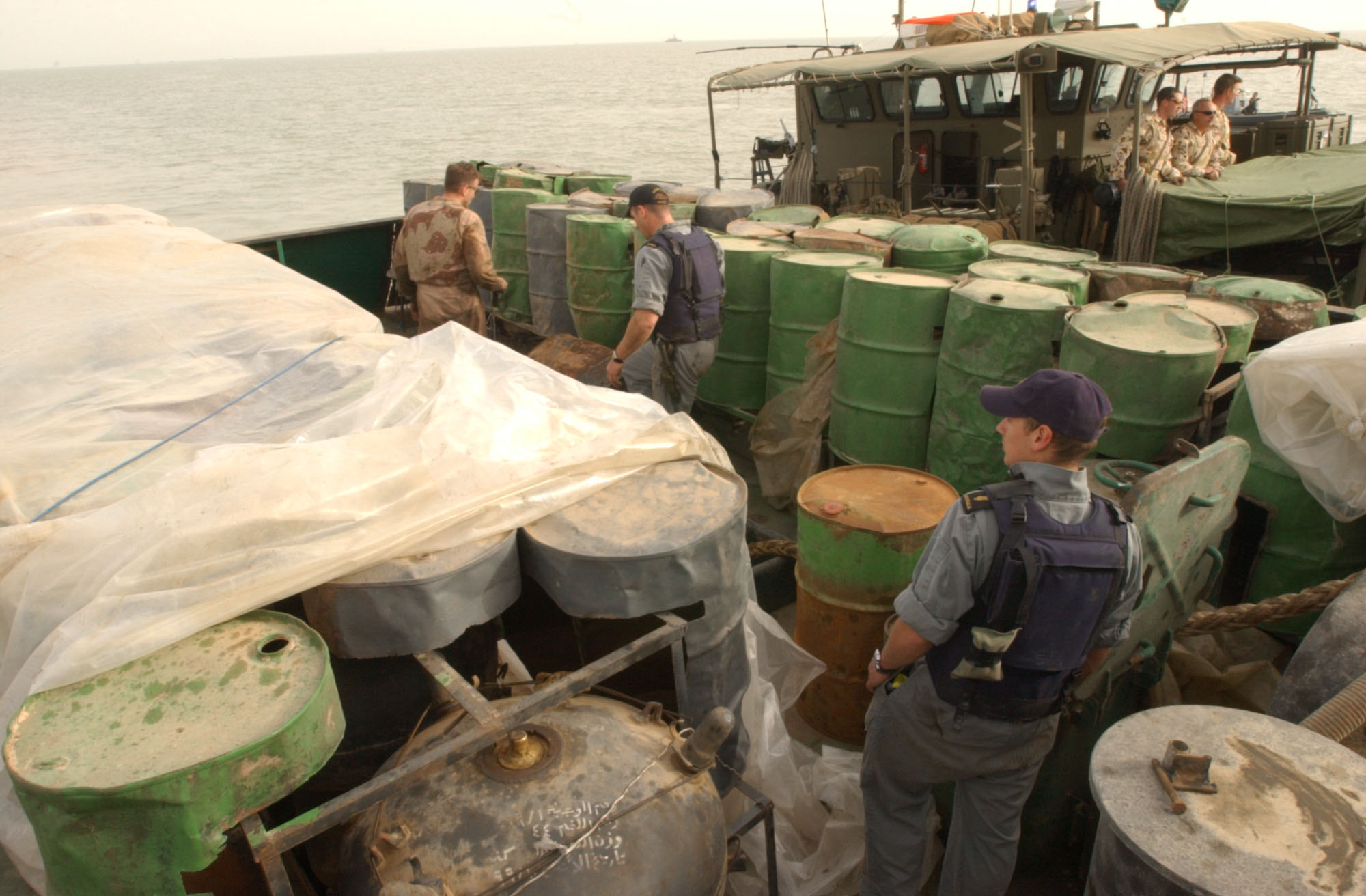 US_Navy_030321-N-4655M-028_Coalition_Navy_Explosive_Ordnance_Disposal_%28EOD%29_team_members_inspect_camouflaged_mines_hidden_inside_oil_barrels_on_the_deck_of_an_Iraqi_shipping_barge.jpg
