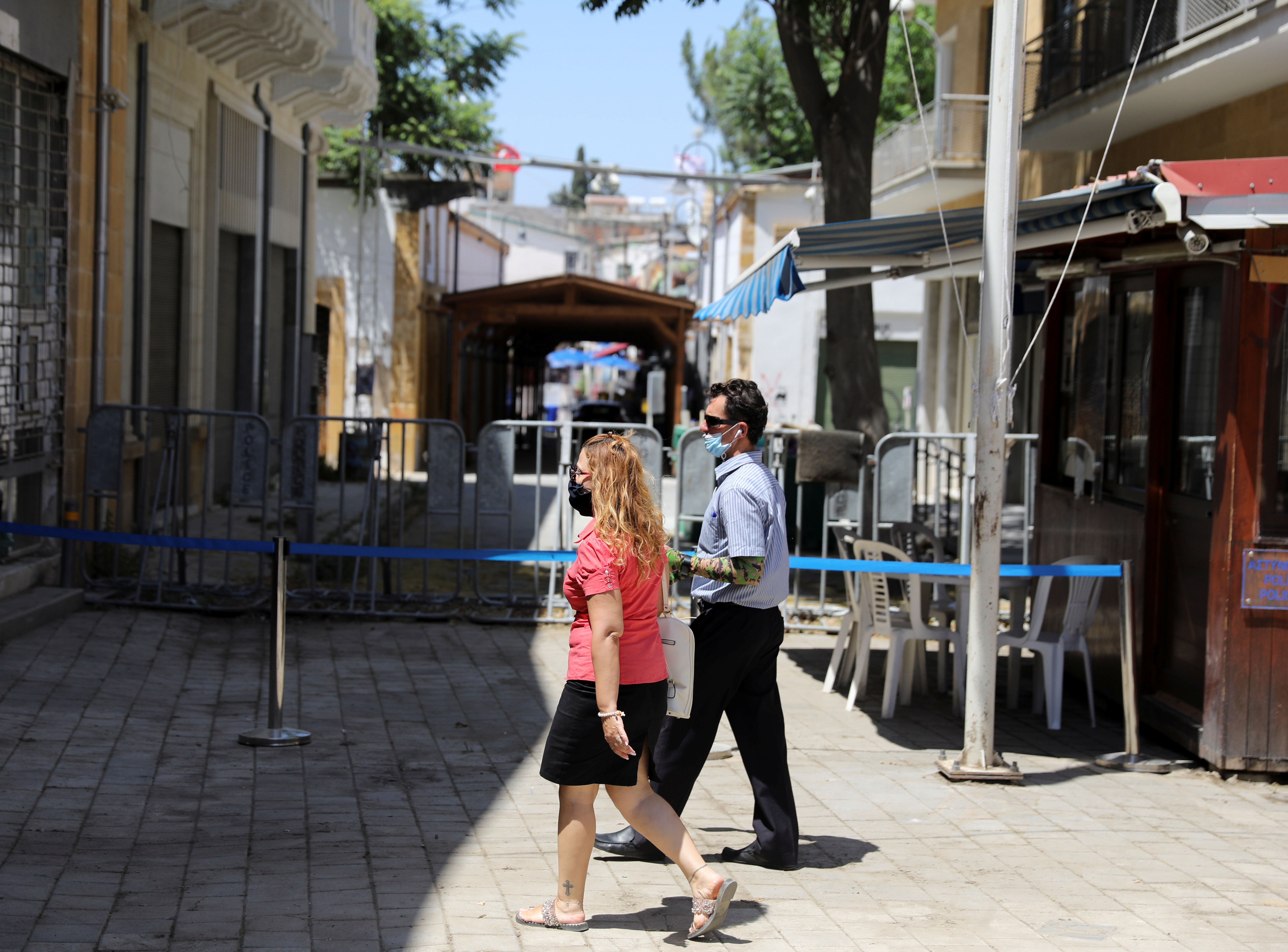 People walk next to the closed Ledra checkpoint of the U.N.-controlled buffer zone in Nicosia,  Cyprus June 2, 2021. REUTERS/Yiannis Kourtoglou