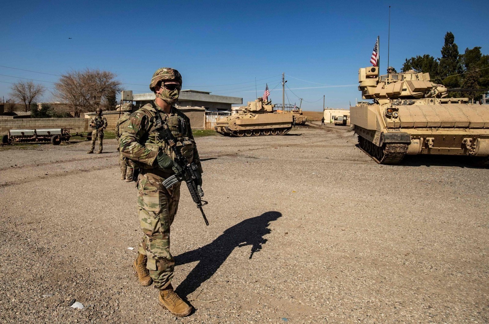 A U.S. soldier walks near a Bradley Fighting Vehicle (BFV) during a patrol in the countryside near al-Malikiyah (Derik) in Hassakeh province, northeastern Syria, Feb. 2, 2021. (AFP Photo)