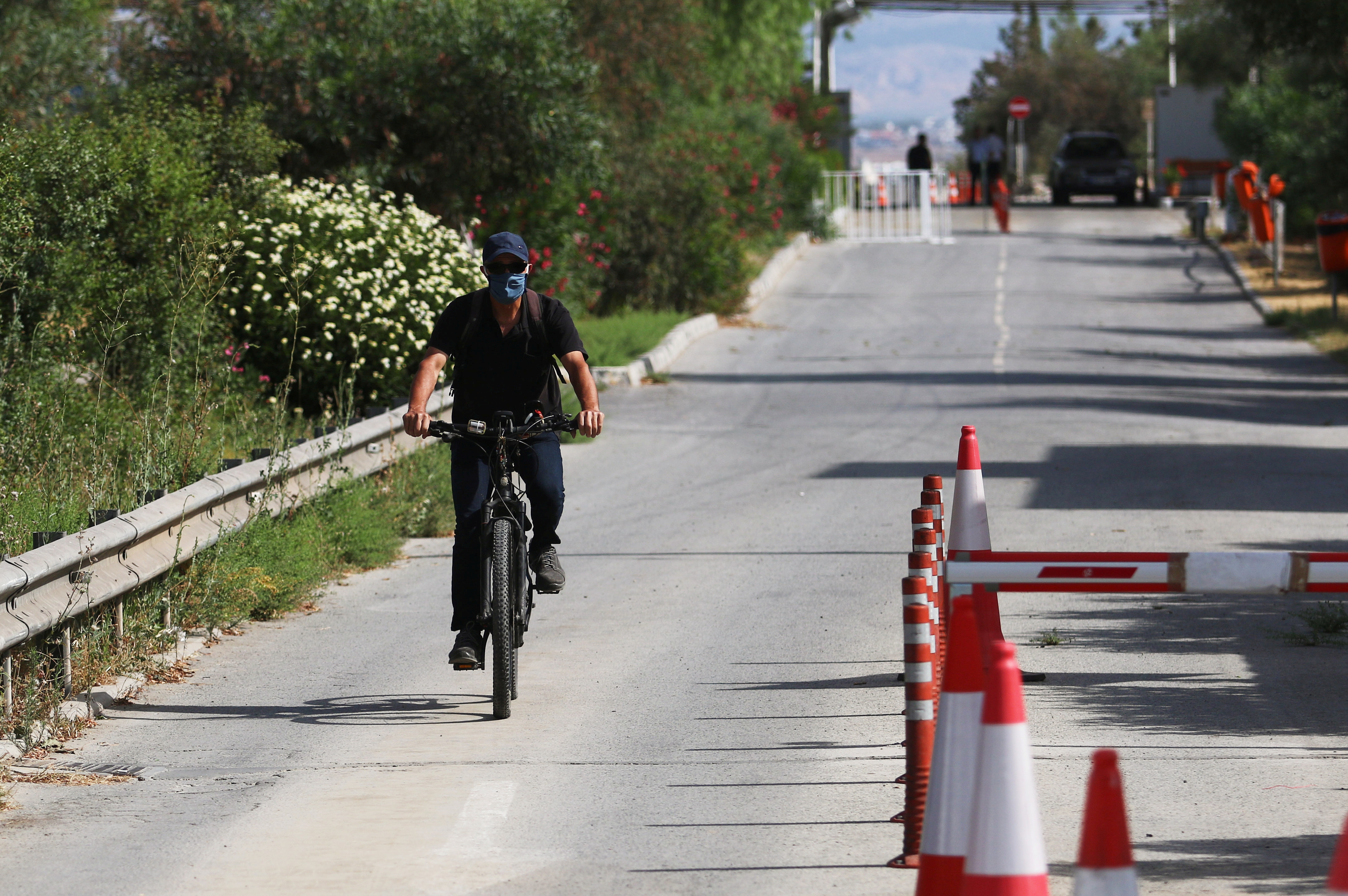 A Turkish Cypriot man wearing a face mask crosses Ayios Dhometios checkpoint on a bicycle, as the spread of the coronavirus disease (COVID-19) continues, in Nicosia, Cyprus June 21, 2020. REUTERS/Yiannis Kourtoglou