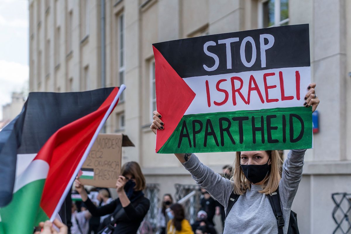 A participant holds up a sign reading Stop Israeli Apartheid during a protest in solidarity with the Palestinians called over the ongoing conflict with Israel in front of the Israeli embassy in Warsaw, 15 May 2021. [WOJTEK RADWANSKI/AFP via Getty Images]