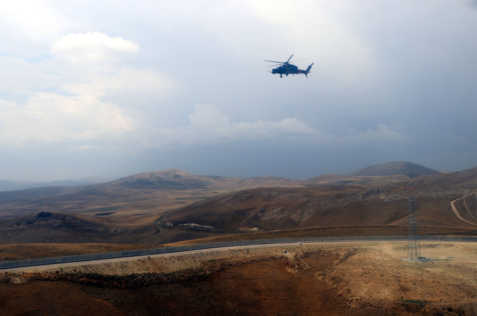 A helicopter flies over the construction of a modular wall across the Turkey-Iran borderline in Van province, eastern Turkey, Aug. 21, 2021. (DHA Photo)