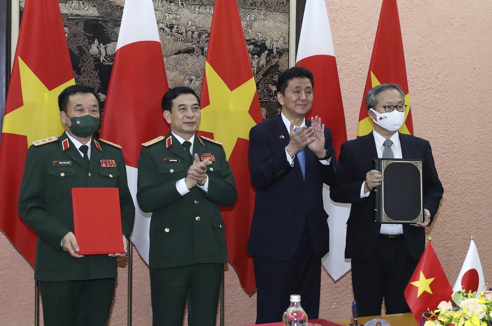 Vietnamese Defense Minister Phan Van Giang, center left, and Japanese Defense Minister Nobuo Kishi, center right, stand for photo with their officials after signing an agreement in Hanoi, Vietnam, Sept. 12, 2021. (AP Photo)