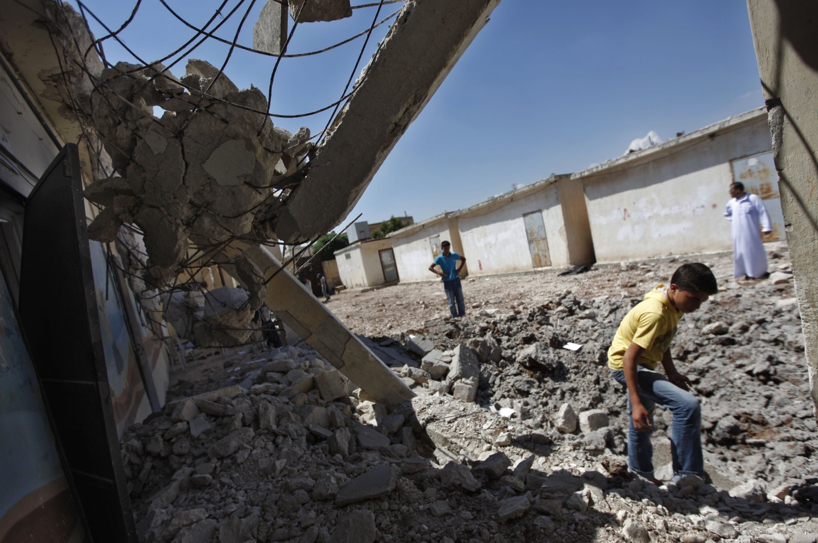 Syrians check the damage at a destroyed school after it was hit by an airstrike killing six Syrians in town of Tal Rifaat on the outskirts of Aleppo, Syria, Aug. 8, 2012. (AP File Photo)