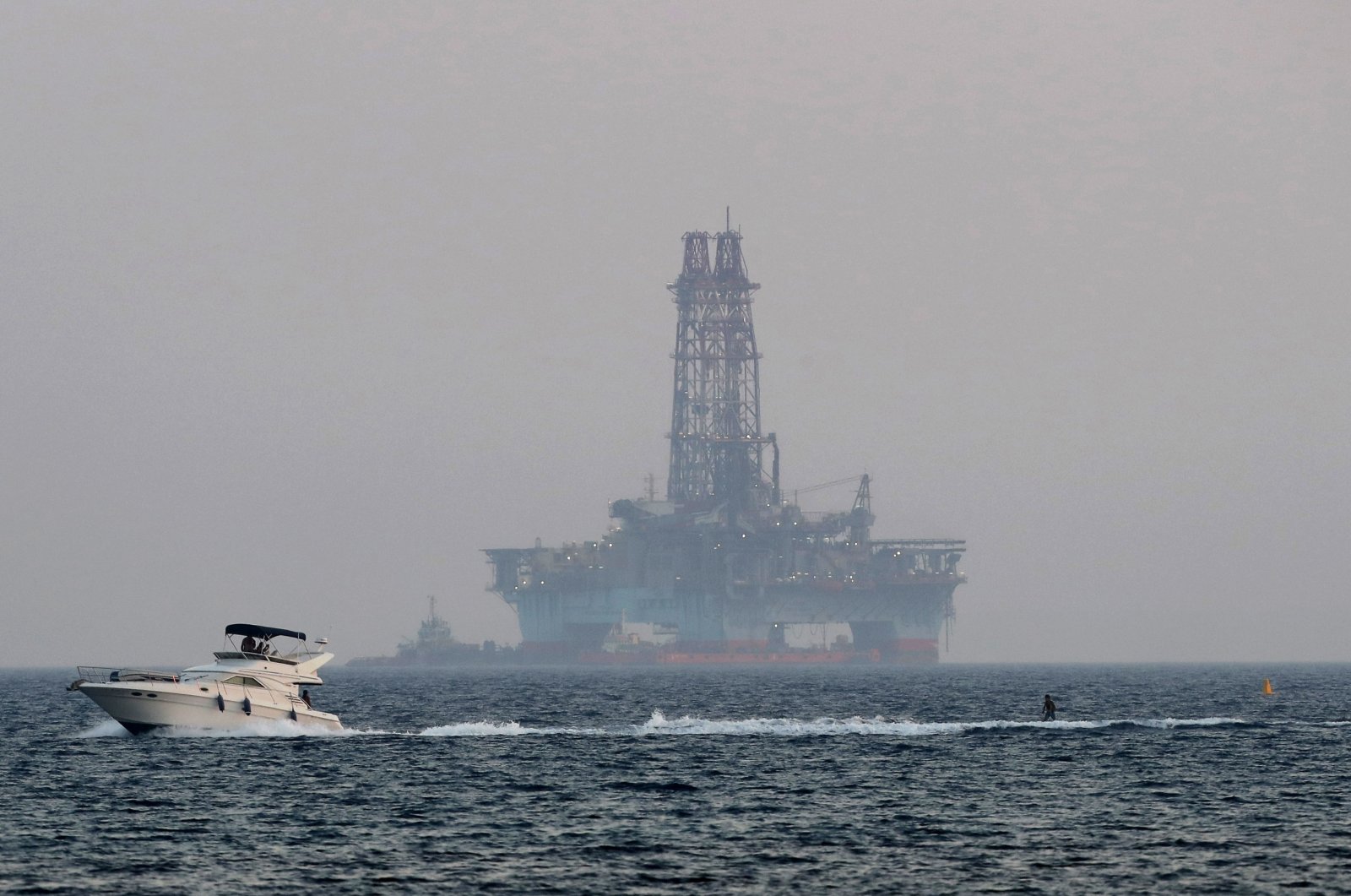 An offshore drilling rig is seen in the waters off Cyprus' coastal city of Limassol as a boat passes with a skier, July 5, 2020. (AP File Photo)