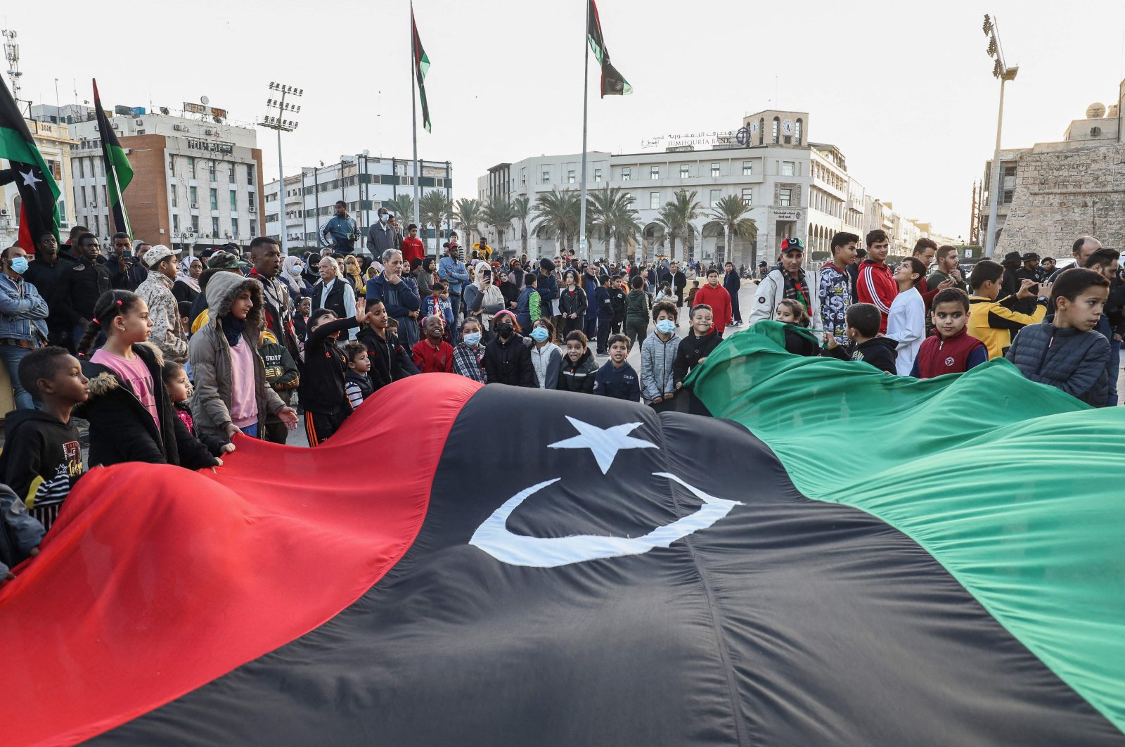 Children wave a giant Libyan national flag as people gather at Martyrs' Square in the center of the capital Tripoli, Libya, Dec. 24, 2021. (AFP Photo)