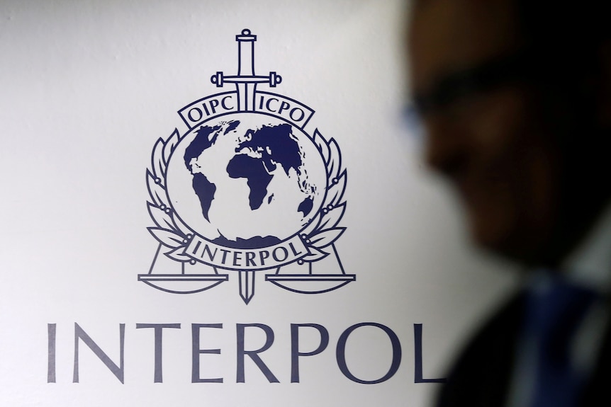 A man passes an Interpol logo