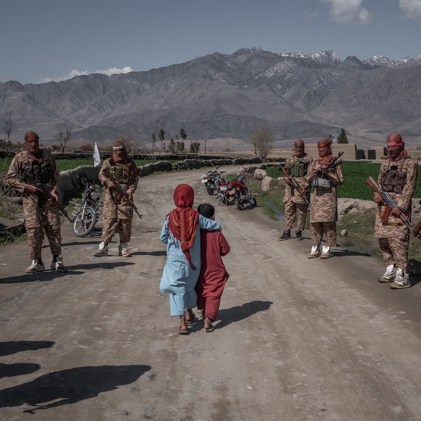 Two boys pass members of a Taliban Red Unit, an elite force, in the Alingar district in March.