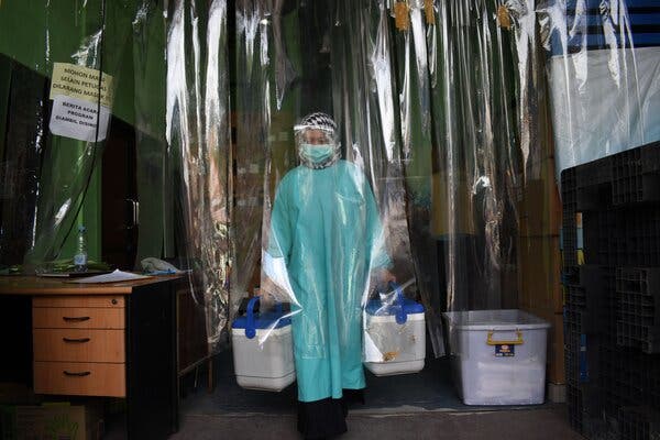 A health worker in Indonesia delivering containers of the Sinovac vaccine. Officials there initially said the Sinovac vaccine had a 68 percent efficacy rate.