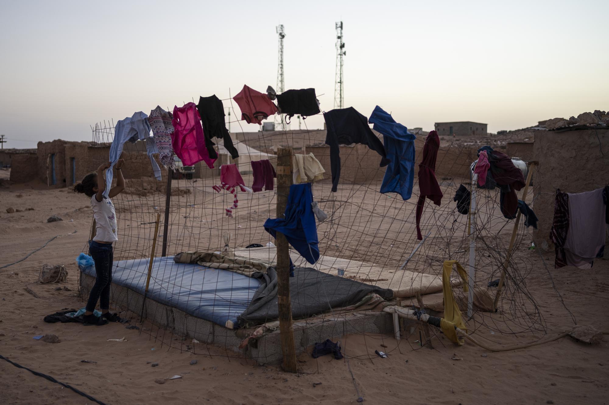 A Sahrawi refugee girl picks-up the laundry in the Boujdour refugee camp, Algeria, Friday, Oct. 15, 2021. (AP Photo/Bernat Armangue)