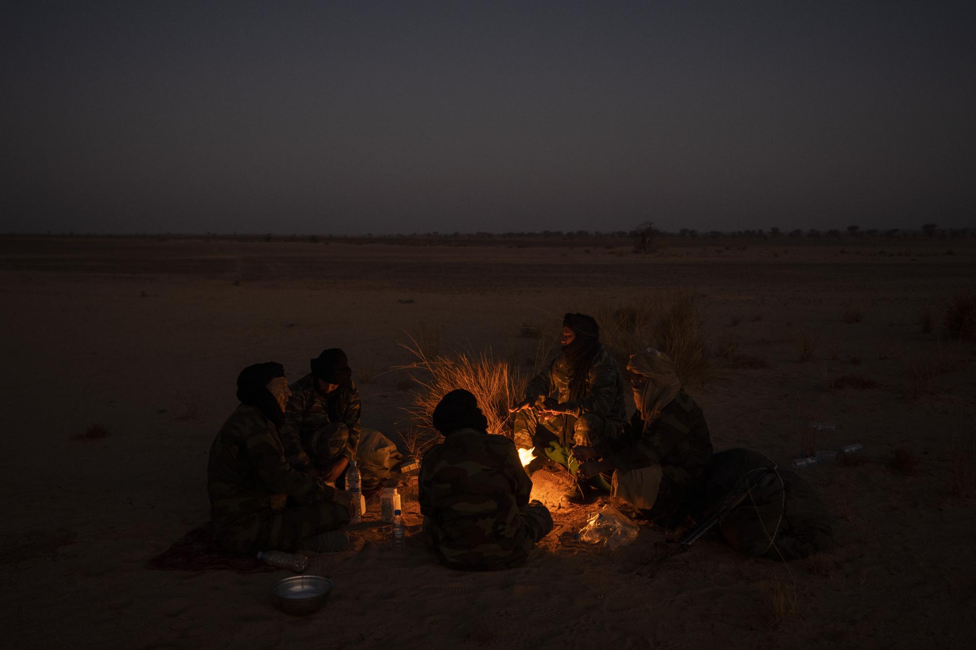 Polisario Front soldiers warm themselves by a fire near Bir Lahlou, Western Sahara, Friday, Oct. 15, 2021. (AP Photo/Bernat Armangue)