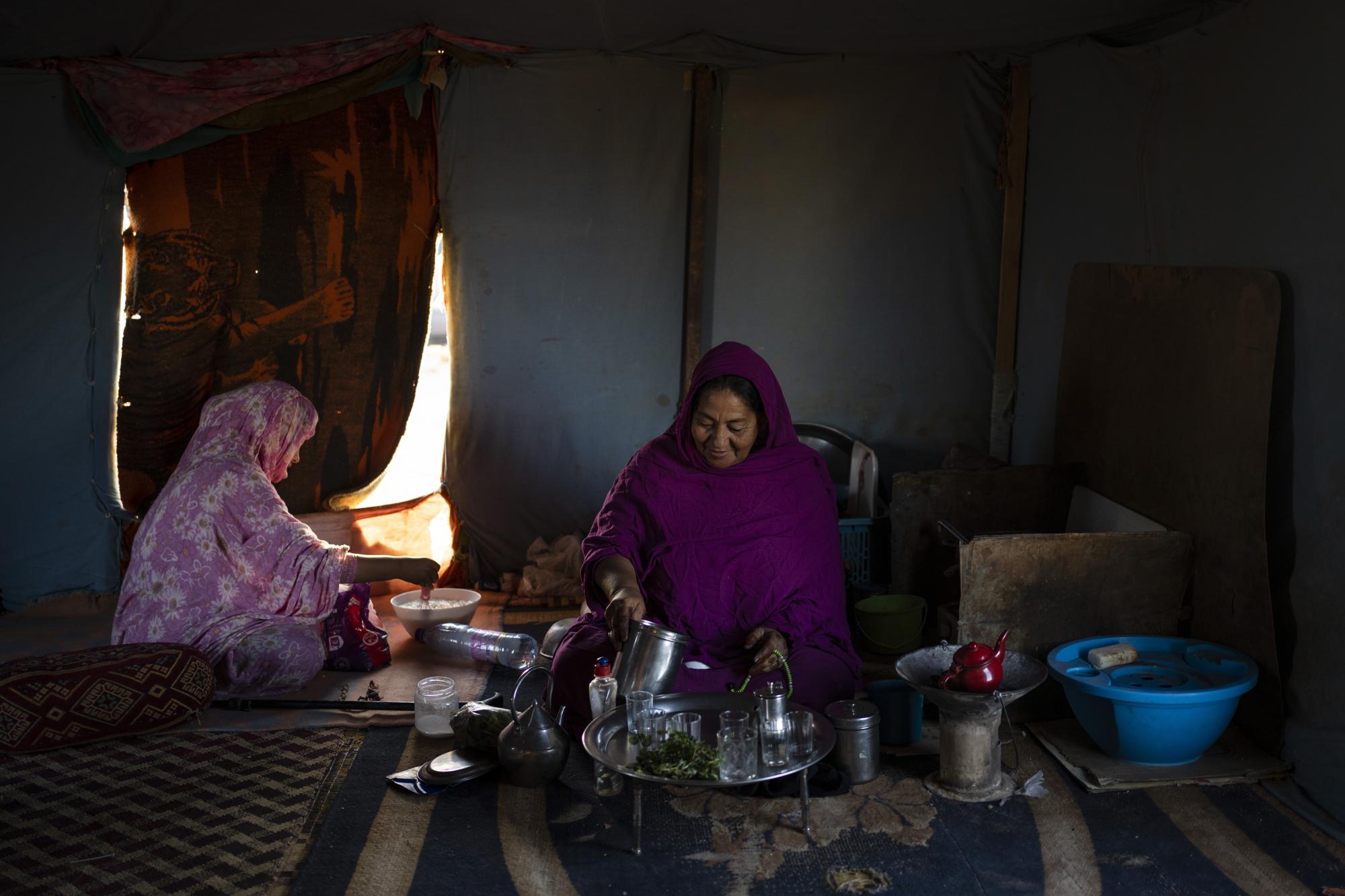 A Sahrawi family prepares breakfast inside their tent in the outskirts of Boujdour refugee camp, Algeria, Saturday, Oct. 16, 2021. (AP Photo/Bernat Armangue)