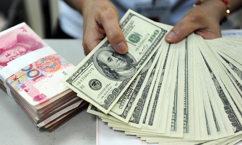 A staff member counts banknotes at a bank in Qionghai of south China's Hainan Province.(Photo: Xinhua)
